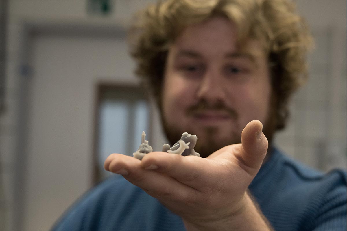 Dennis hält in seiner Hand einen Frosch, der auf dem 3D-Drucker ausgedruckt wurde