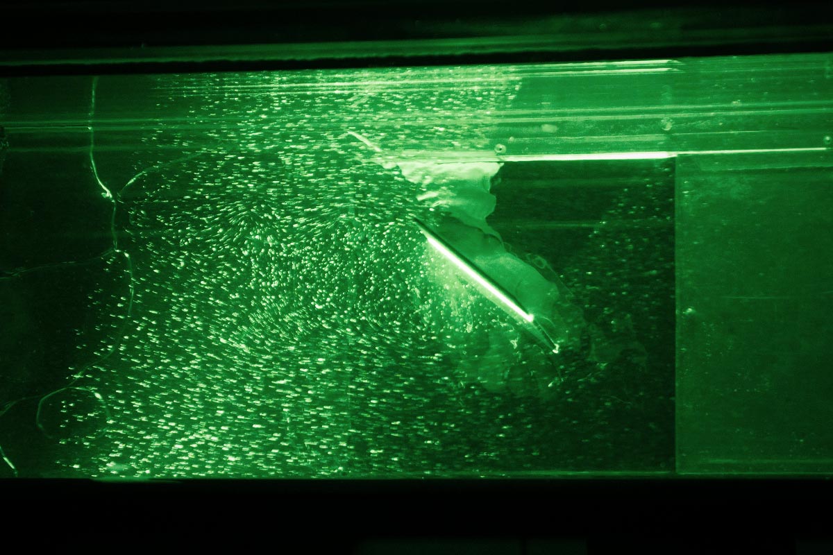 Grün beleuchteter Strömungskanal. Laserstrahlen und Mikropartikel machen hier auch kleinste Verwirbelungen sichtbar